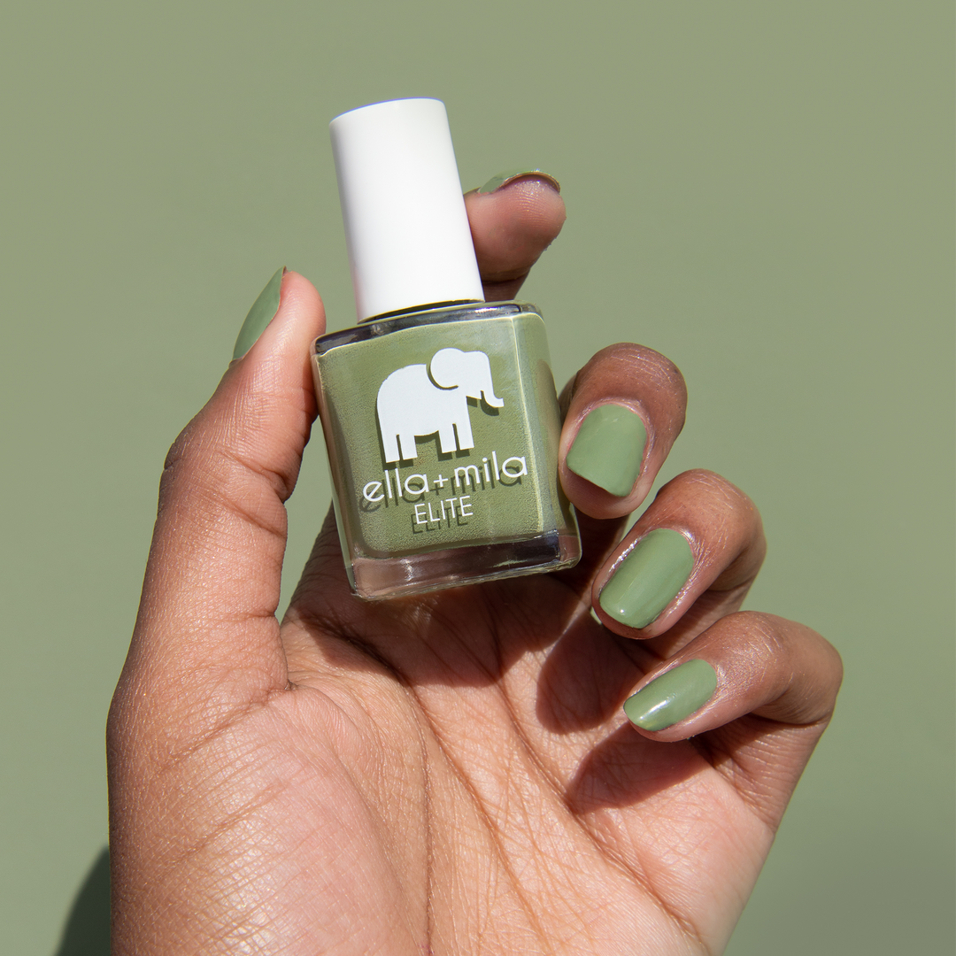 Paradise Isle army green nail polish on a deep skin tone, holding the bottle on a green background