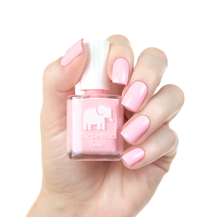 Pink Me Up baby pink nail polish manicure on a light skin tone with the bottle