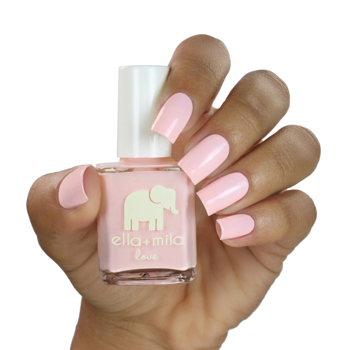 Pink Me Up baby pink nail polish on a medium skin tone, hand holding the bottle