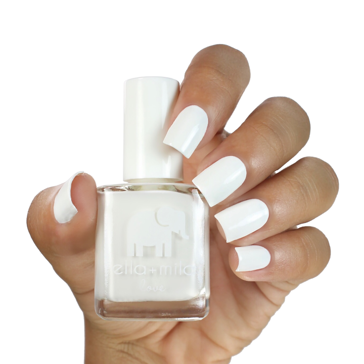 Pure Love white nail polish on a medium-deep skin tone, hand holding the bottle