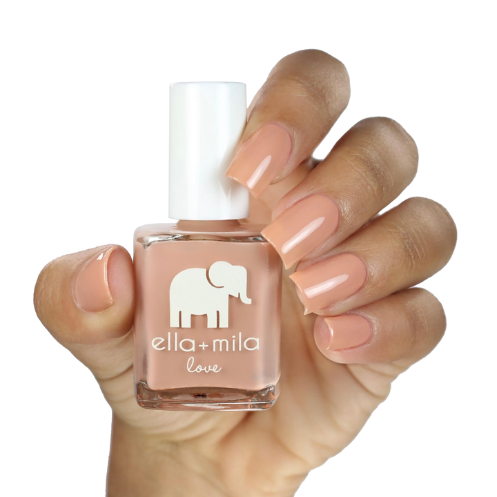 Sandy Toes nude caramel nail polish on a medium skin tone, hand holding the bottle