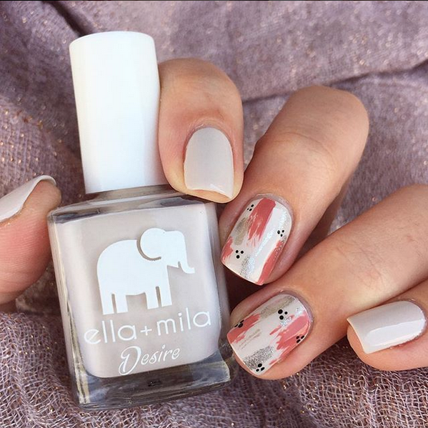 Stonehearted grey nail polish with floral accent nail art, holding the bottle