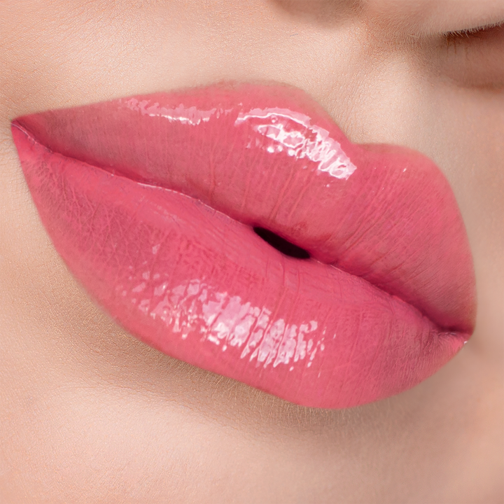 Glossy Stripped coral pink lip gloss on lips, light skin tone close-up