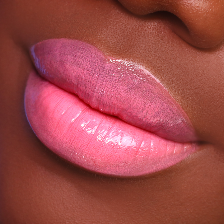 Glossy Stripped coral pink lip gloss on lips, deep skin tone close-up
