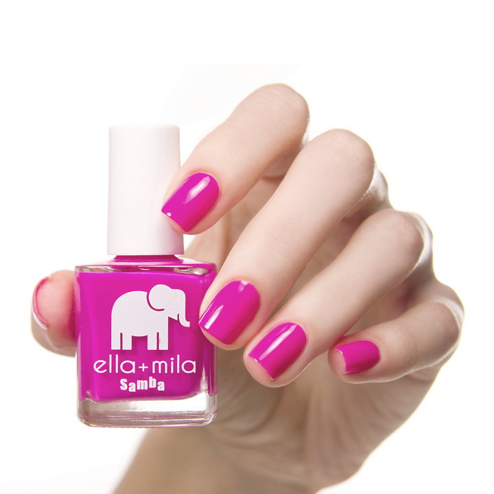Sun Has Set purple-pink nail polish on a medium skin tone, hand holding the bottle