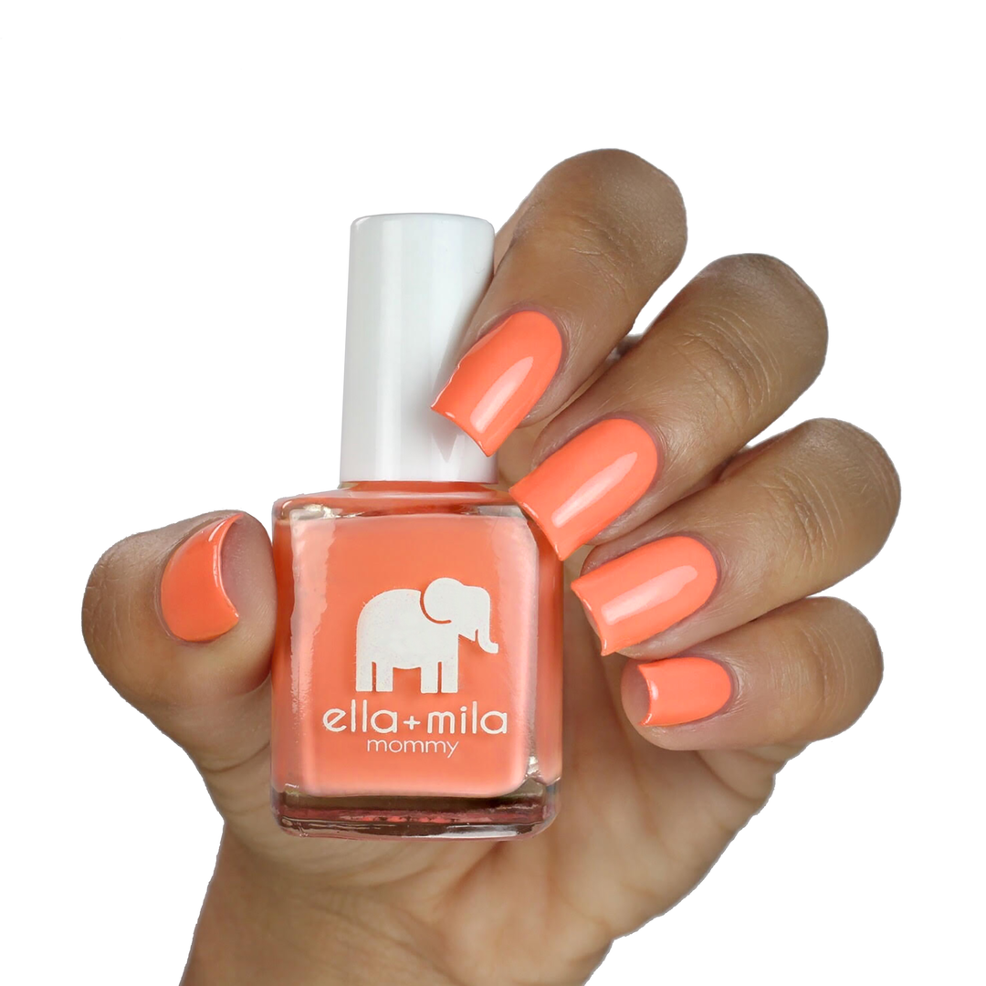 Sunkissed coral orangesicle nail polish on a medium skin tone, hand holding the bottle