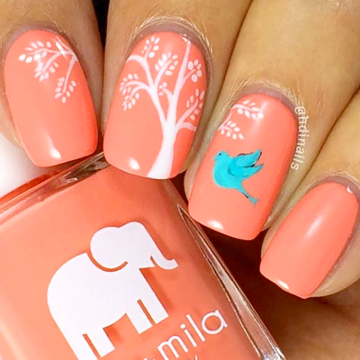 Sunkissed coral nail polish with white tree branch and bird nail art