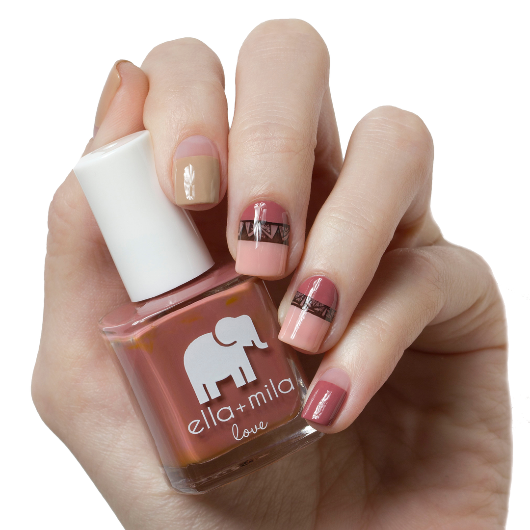 Til Forever mauve nail polish with nude and gold stripe accent nails, holding the bottle