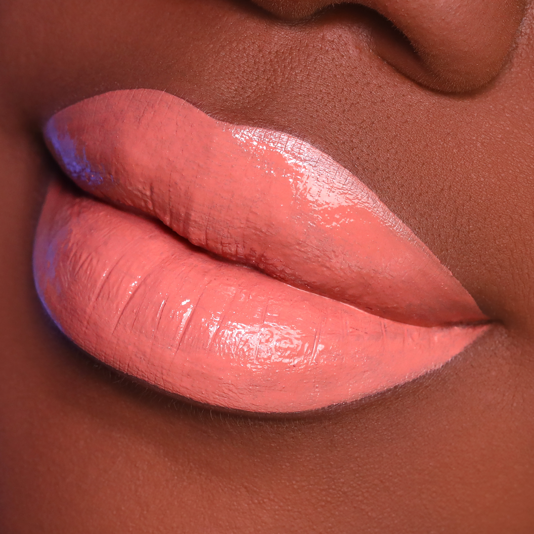 Twisted peachy nude lipstick on lips, deep skin tone close-up