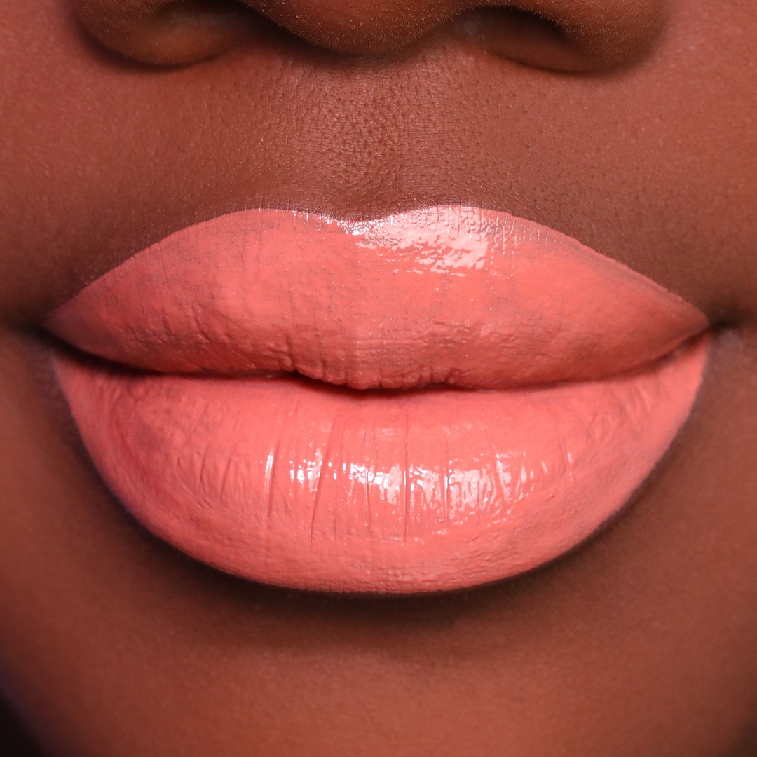 Twisted peachy coral lipstick on lips, medium-deep skin tone