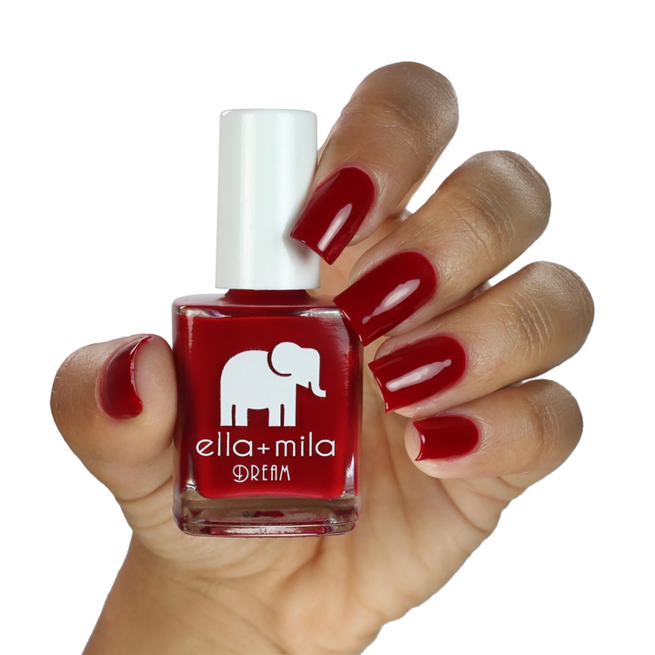Unwrap Me festive red nail polish on a medium skin tone, hand holding the bottle