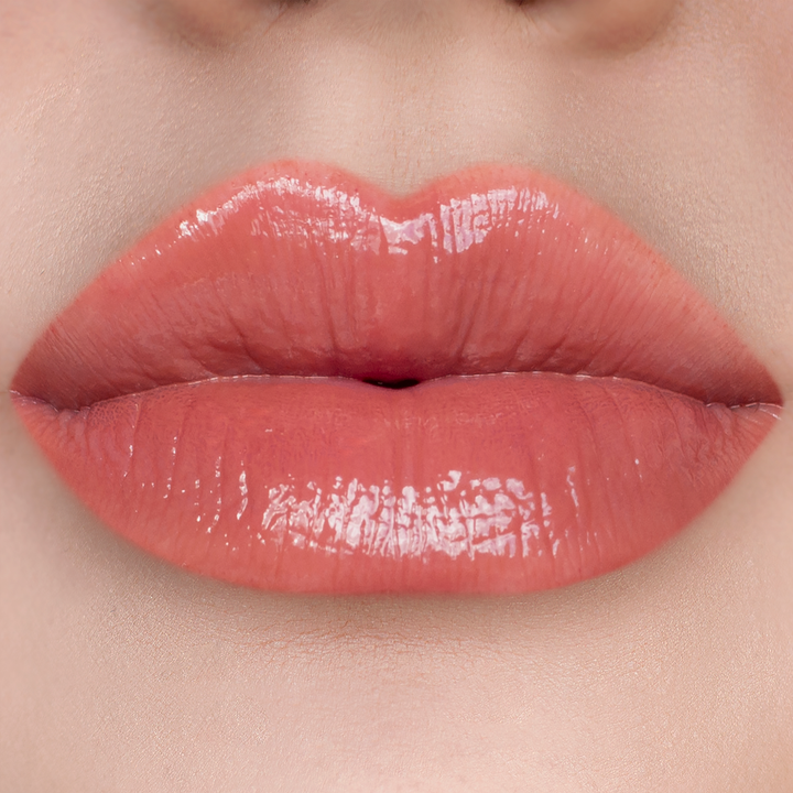 Vibes warm nude coral lip gloss on lips, light skin tone